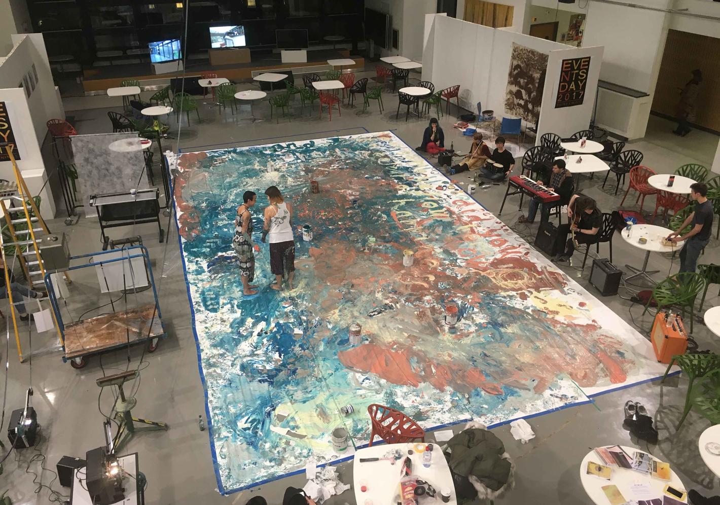 Large colourful painting on the floor of a warehouse studio