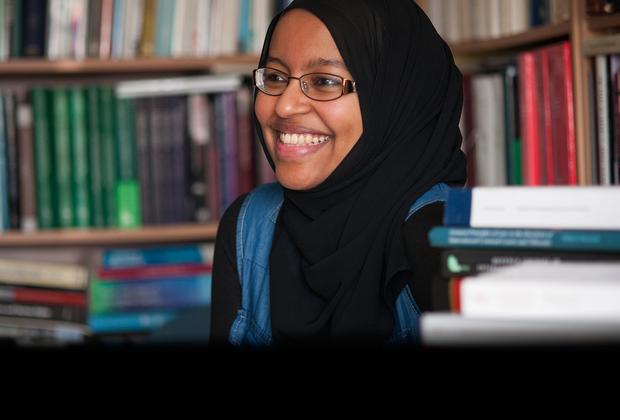 A Muslim female student smiling in a library